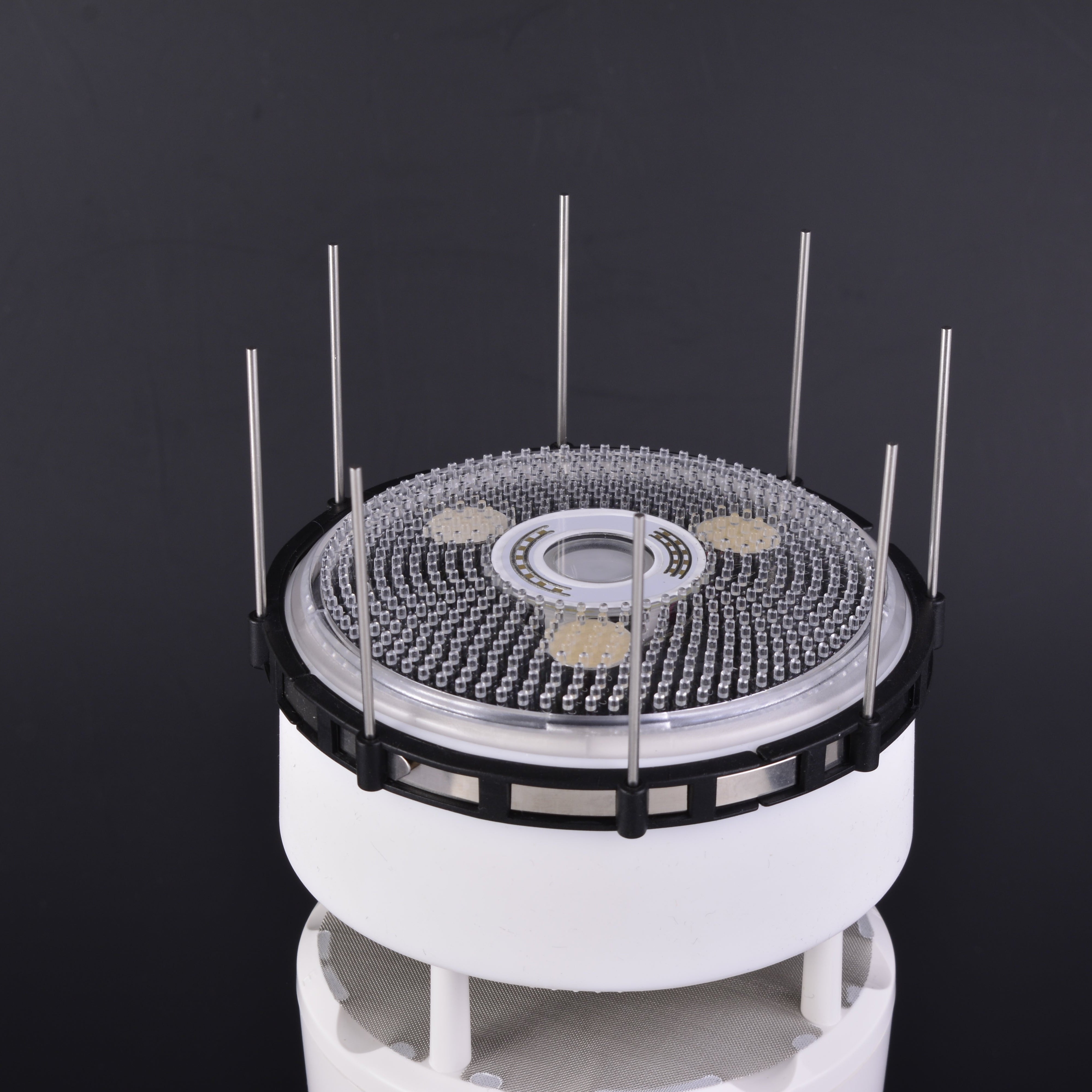Rotating display stand with circular platform and vertical rods on a black background