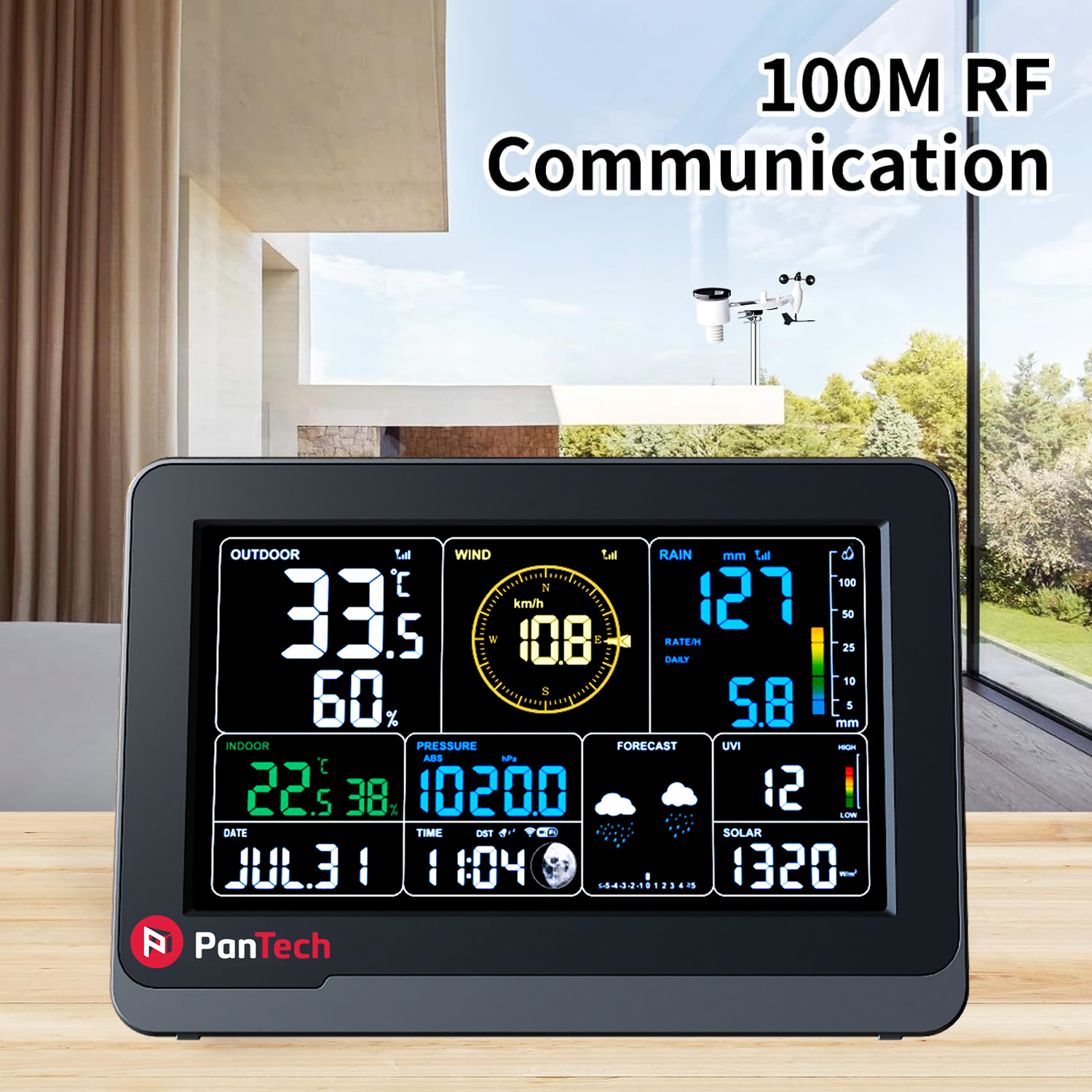 The PanTech colour weather station display console sitting indoors on a wooden desk, demonstrating its reliable 100M RF Communication range. It is shown wirelessly receiving real-time climate data from the outdoor sensor array mounted outside in the background.